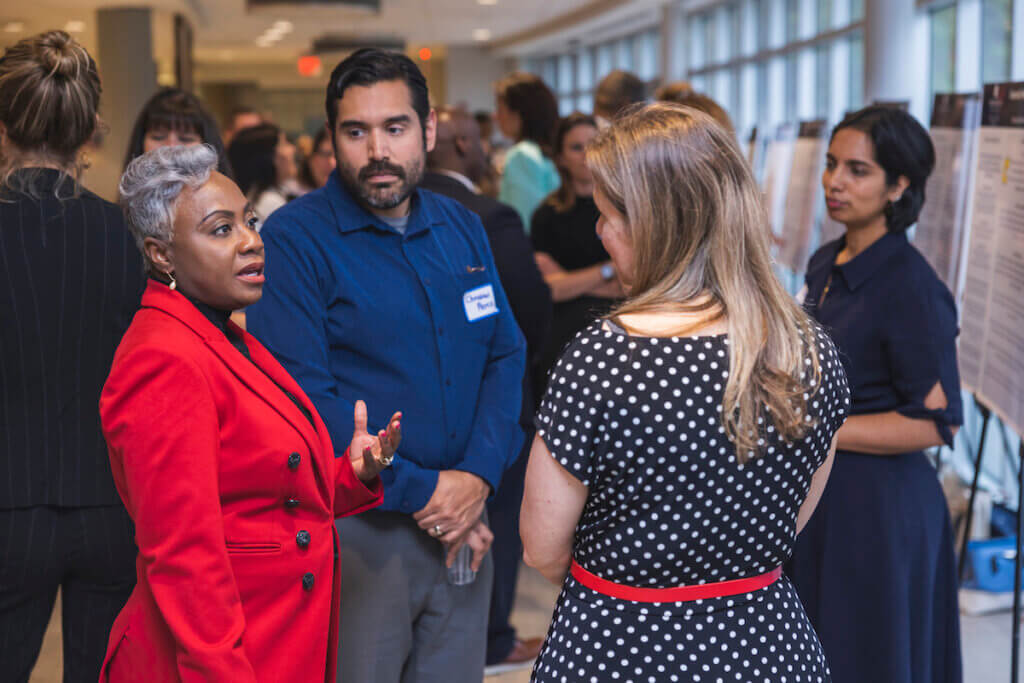 Professional speaking to circle of professionals, with other pros in the background