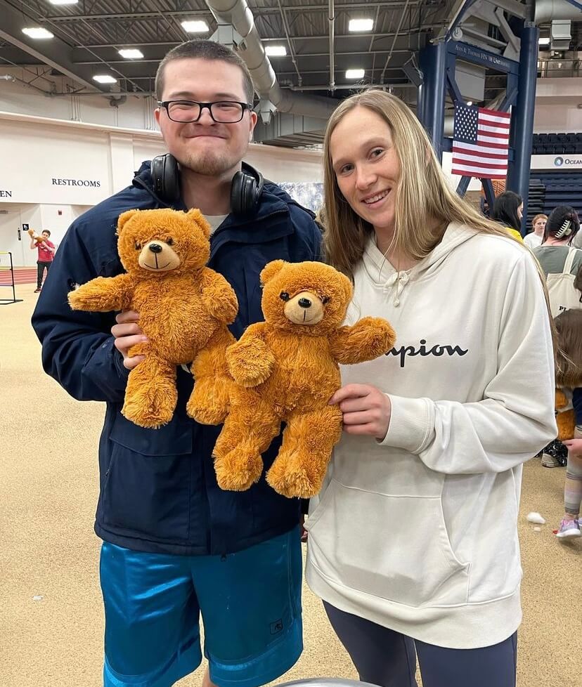 Students participating in a Best Buddies Event, holding teddy bears facing the camera. 