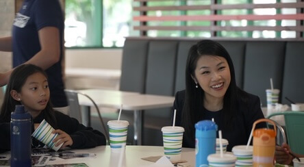 Woman and child smiling at a table in a dining hall,