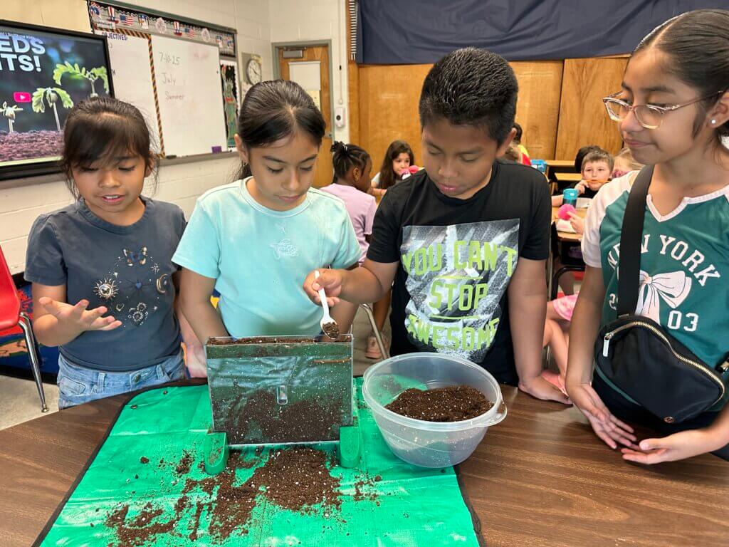 Children measuring soil for a project.