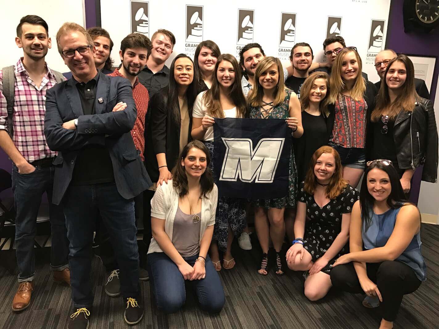 Students and faculty from the university's Music, Communications, and Business programs, standing together for a group photo in the Grammy Museum at L.A. Live