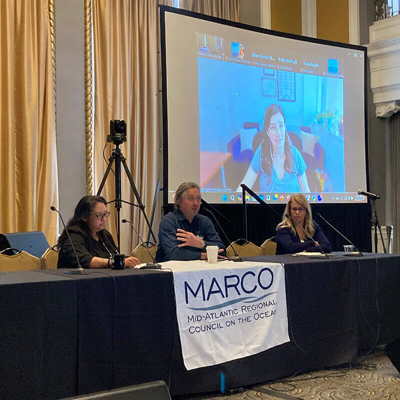 A panel talk with three speakers seated behind a table.