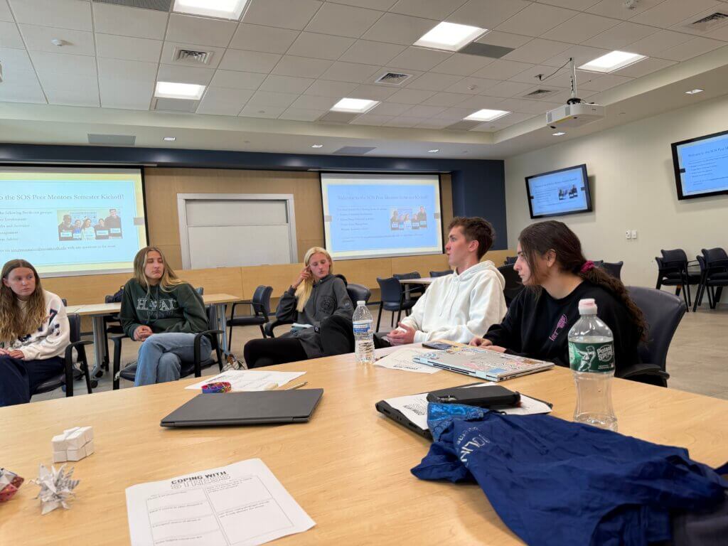 Five people discuss around a table.