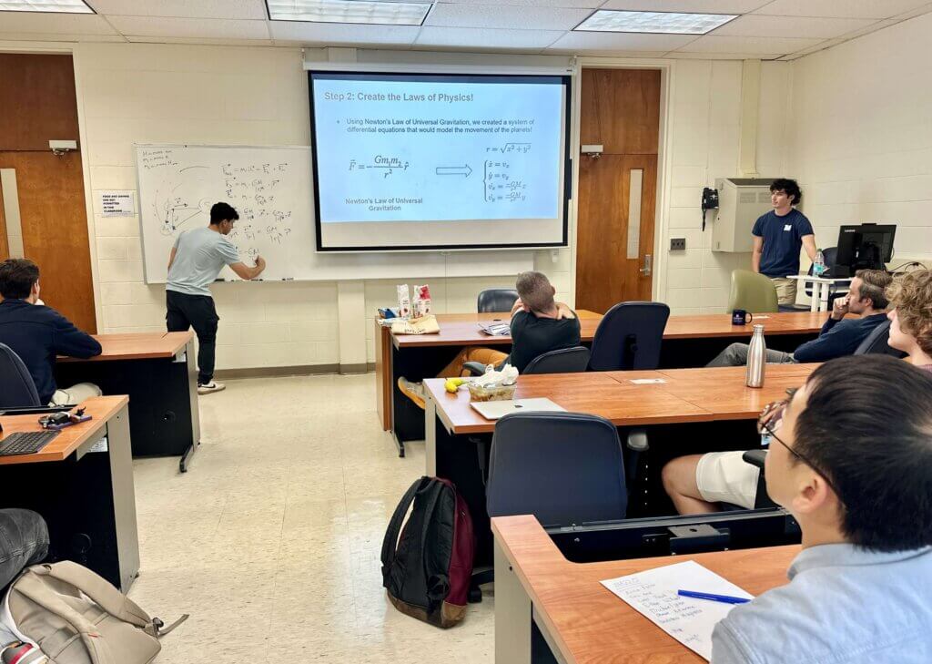 Man writing mathematical symbols on board while audience watches