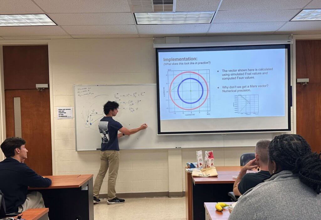 Man writing mathematical symbols on board while audience watches