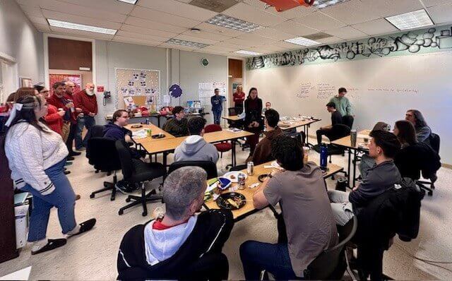 Gathering of students and professors eating together in a classroom.
