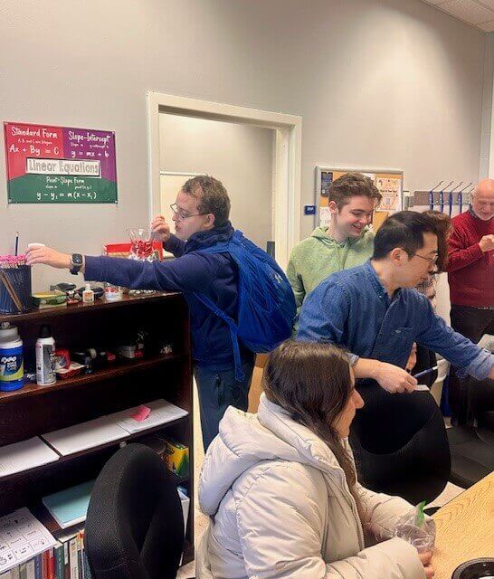 Students and professors reaching for math supplies during party