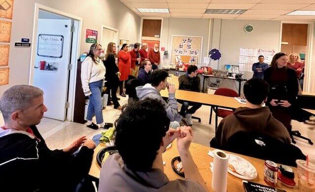 Gathering of students and professors eating together in a classroom.