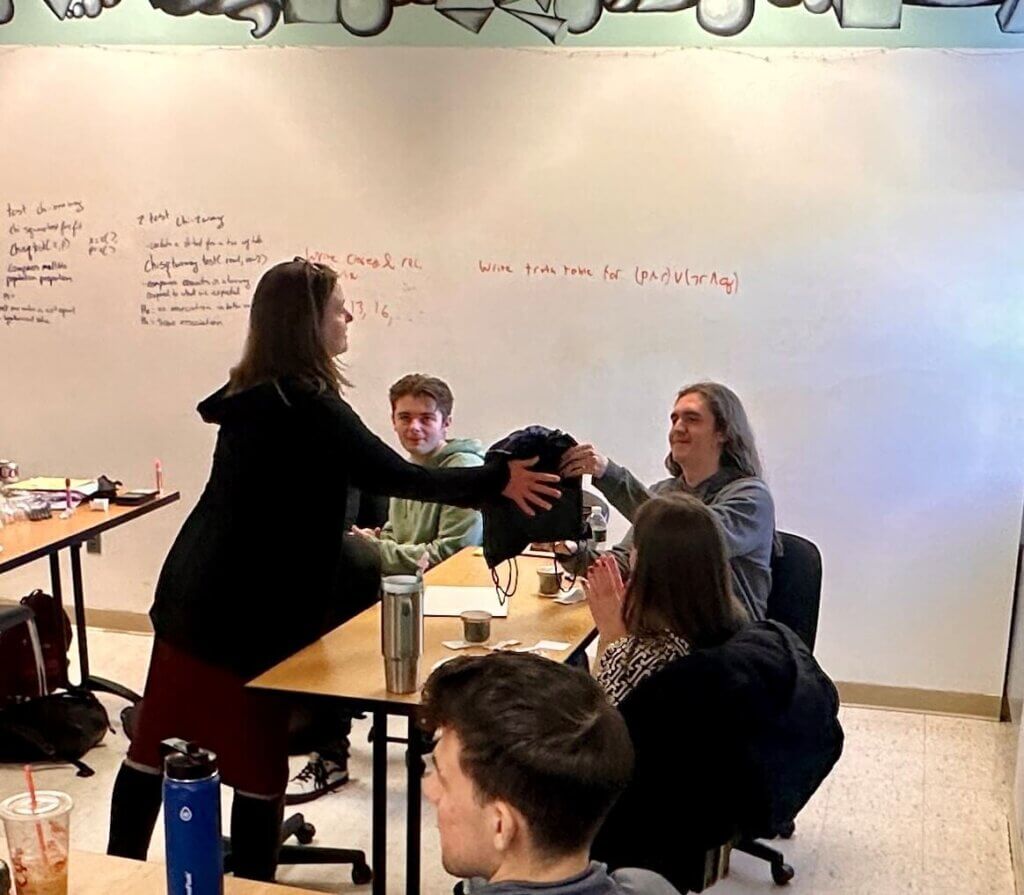 Two party guests exchanging a gift over a classroom table