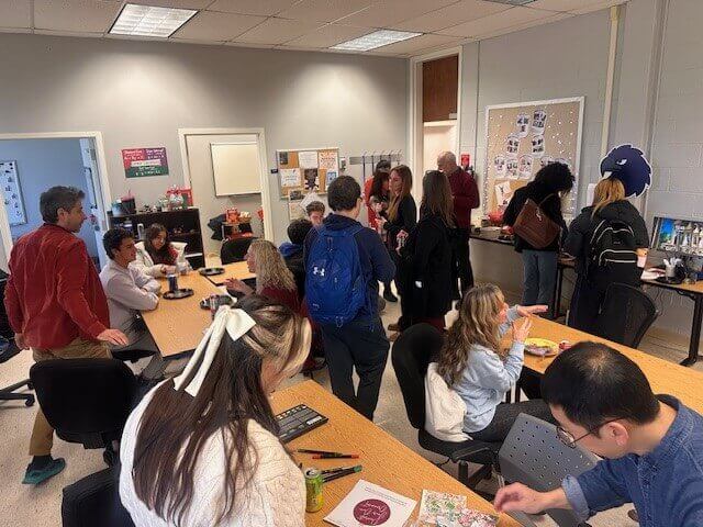 Gathering of students and professors eating together in a classroom.