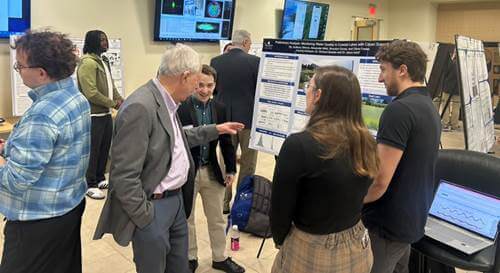Professor looks over students' poster presentation