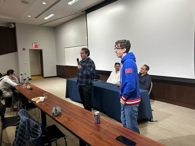 Profesor and student speaking to audience