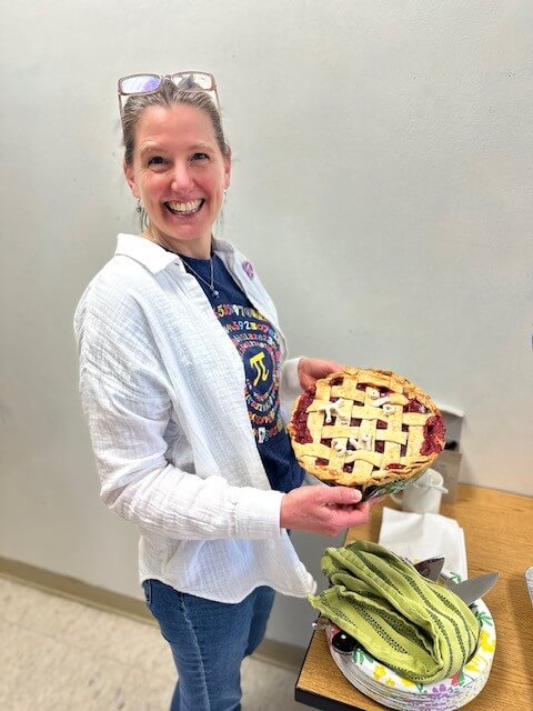 Woman in a t-shirt with the math symbol for pi, holding a baked pie.