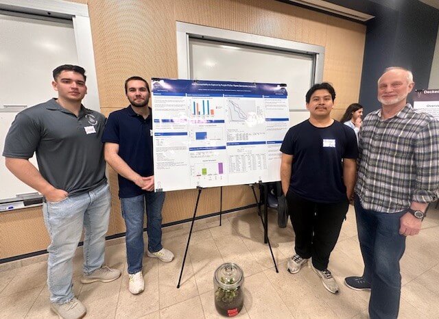 Three students and professor near poster presentation