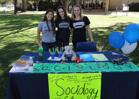 Three students tabling outside for the Sociology Club
