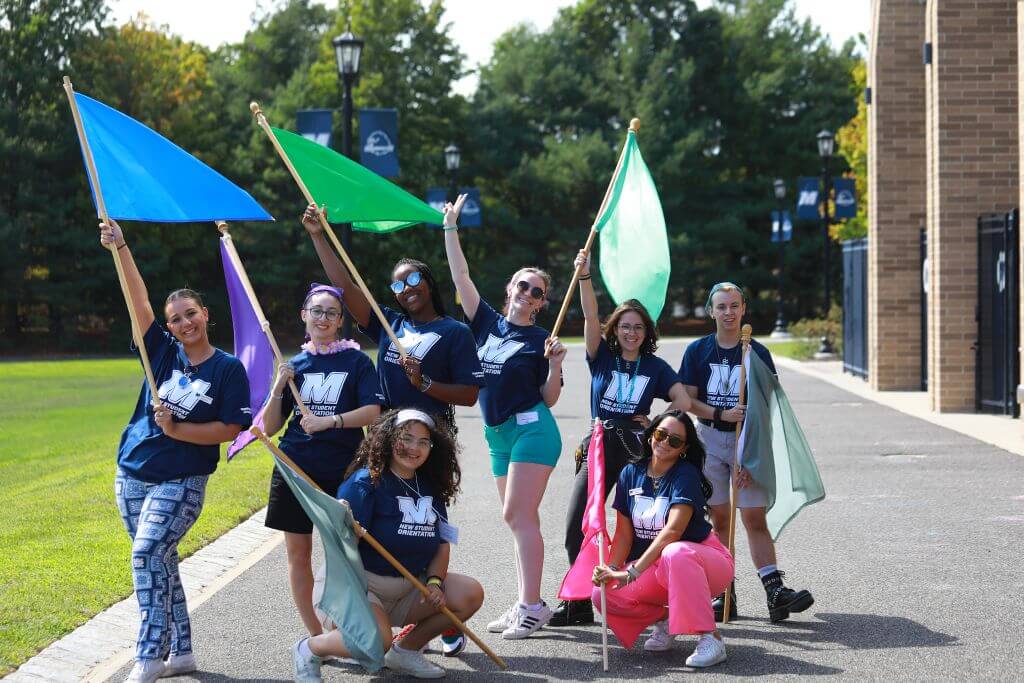A group of students wearing Monmouth shirts while holding flags