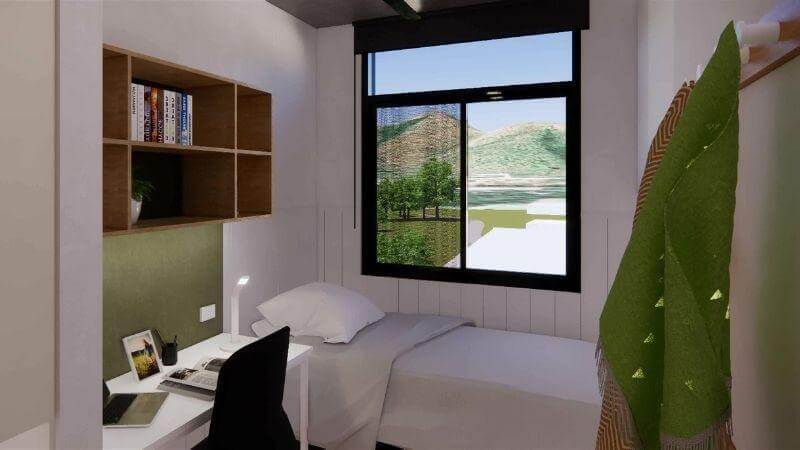 A well-lit room with a desk, bed, hanger, window, an built-in shelf above the desk.