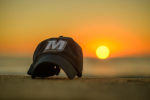 Photo of Monmouth University cap sitting on the beach at West Long Branch NJ at sunrise