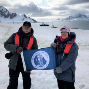 Jim and Debbie Nickels holding Monmouth University flag in Antarctica, 2020.