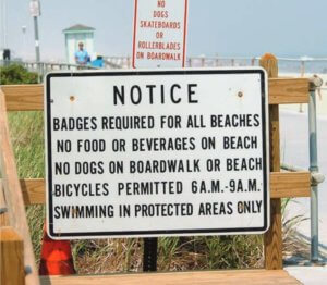 Photo image of boardwalk notice of beach badge requirements along with rules and regulations.