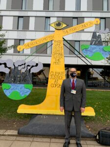 Photo of Dr. Randall Abate in front of art work designed for COP26 conference