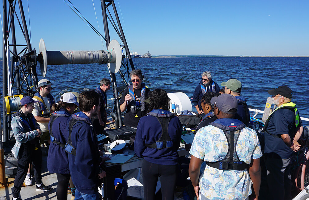 Professor Jason Adolf demonstrates some equipment on the deck of the R/V Heidi Lynn Sculthorpe for students from the National Oceanic and Atmospheric Administration's Inclusive Fisheries Internship Program.