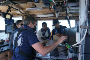 NOAA internship students with faculty leaning how equipment works from faculty member. 