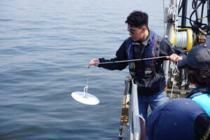 A student uses a Secchi disc to measure water clarity.