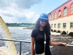 Mauro stands aboard vessel with water passing through a dam in the background. 