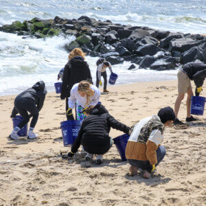 Several students cleaning litter from a beach.