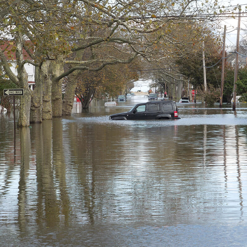 A stalled car on a flooded residential street.