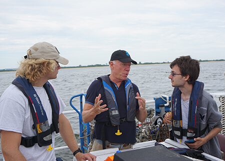 Tony MacDonald speaking to two students aboard a vessel