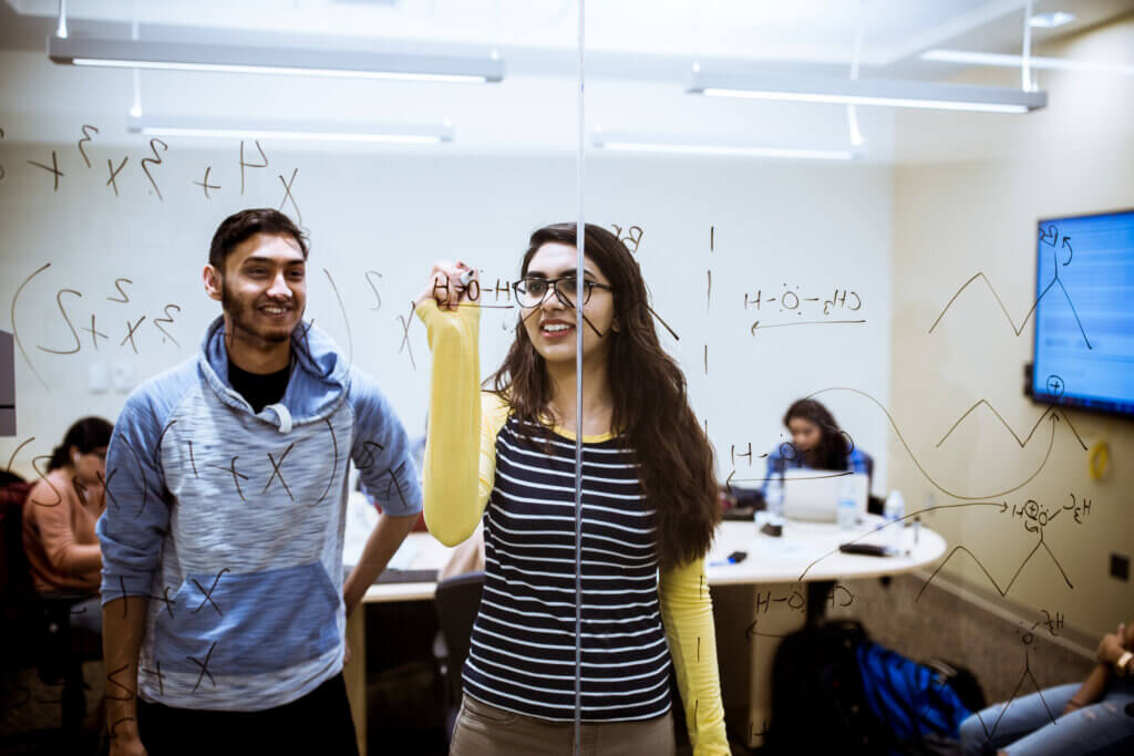 A woman writing equations on a glass wall